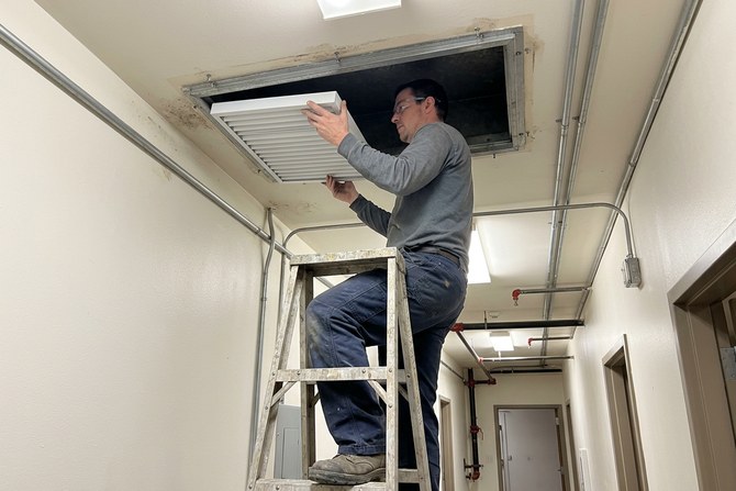 Clean white filter being set into an open ceiling vent